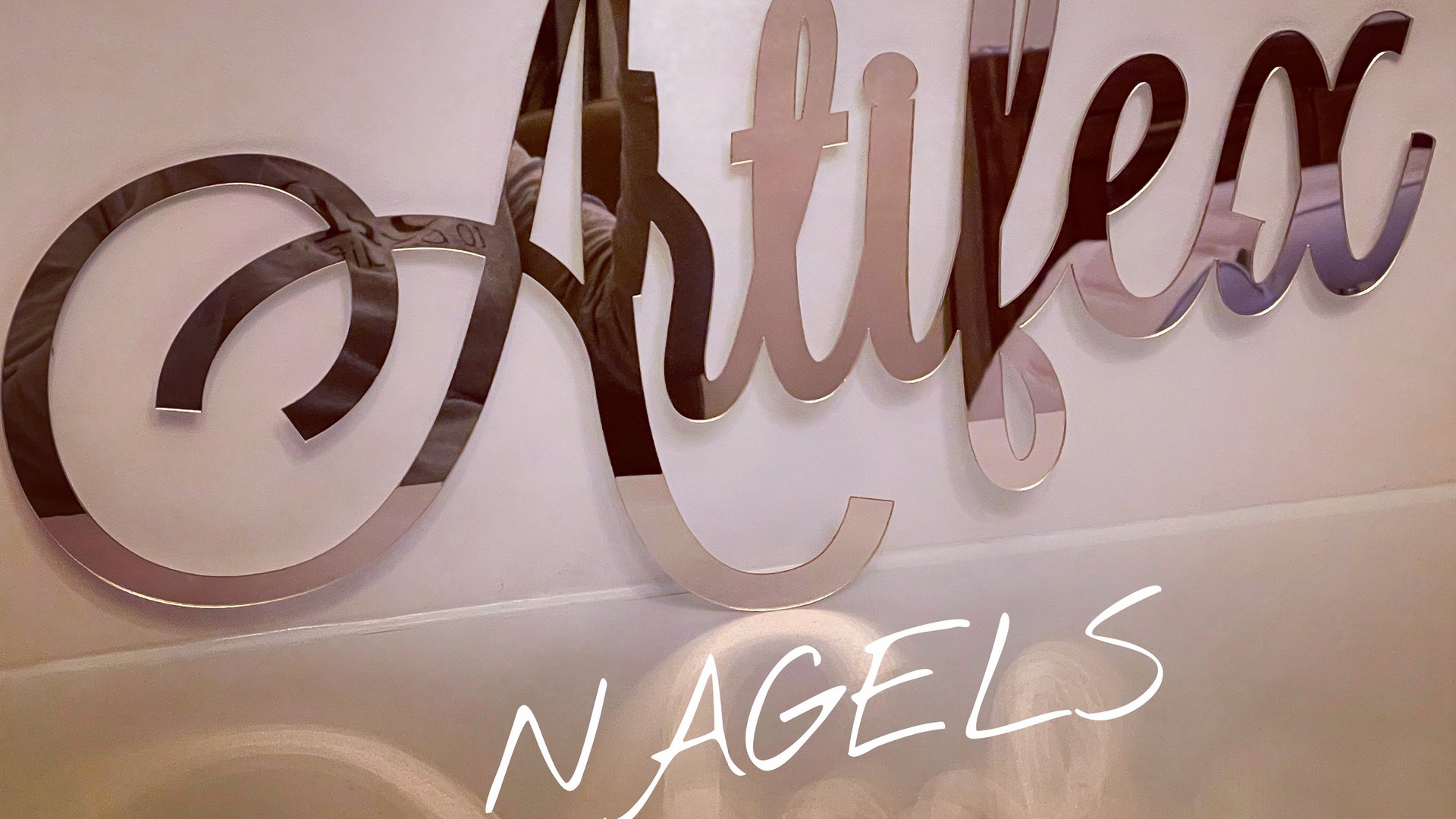 De spiegelende letters Artifex aan de muur van de salon, met nagels in wit handschrift